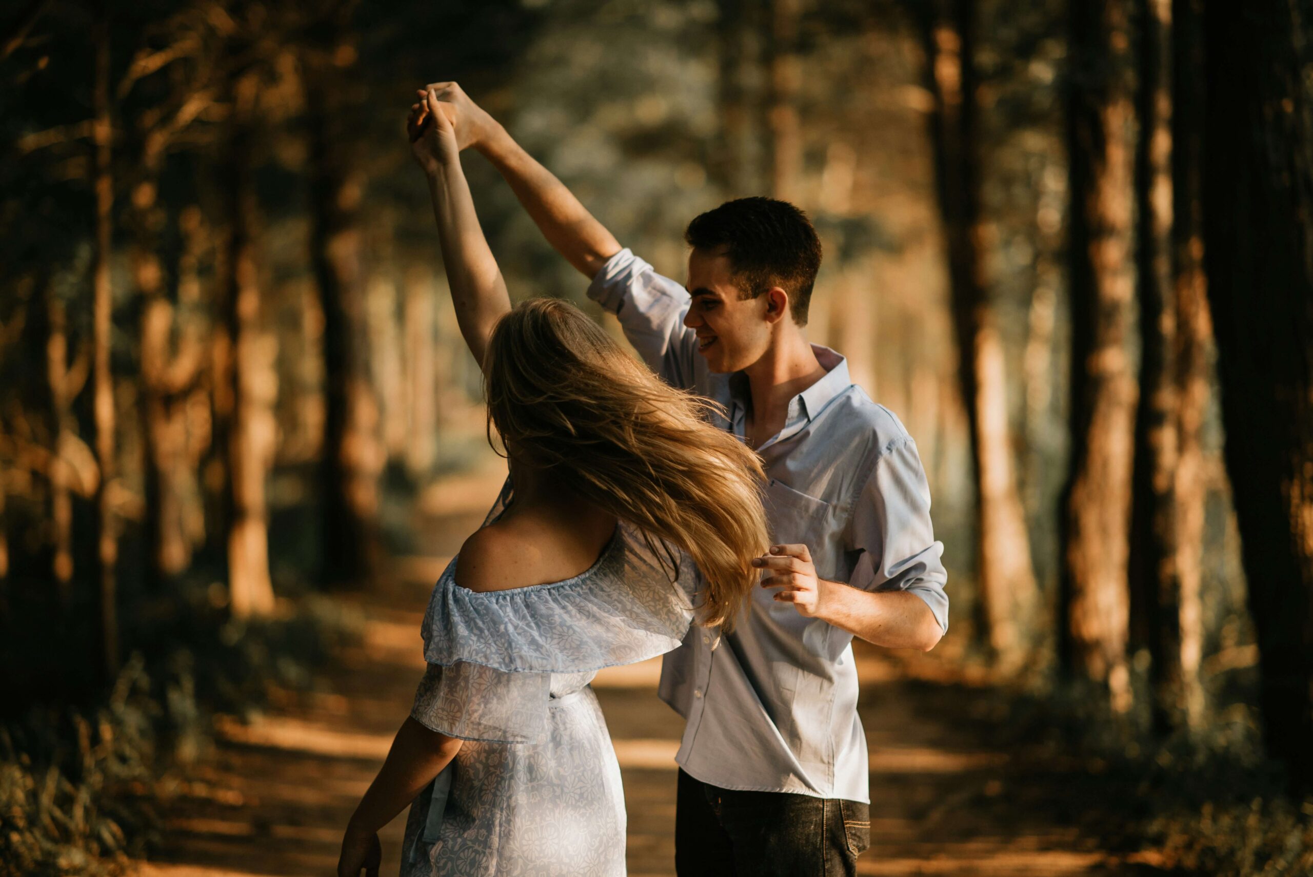 man and woman dancing in aisle of trees