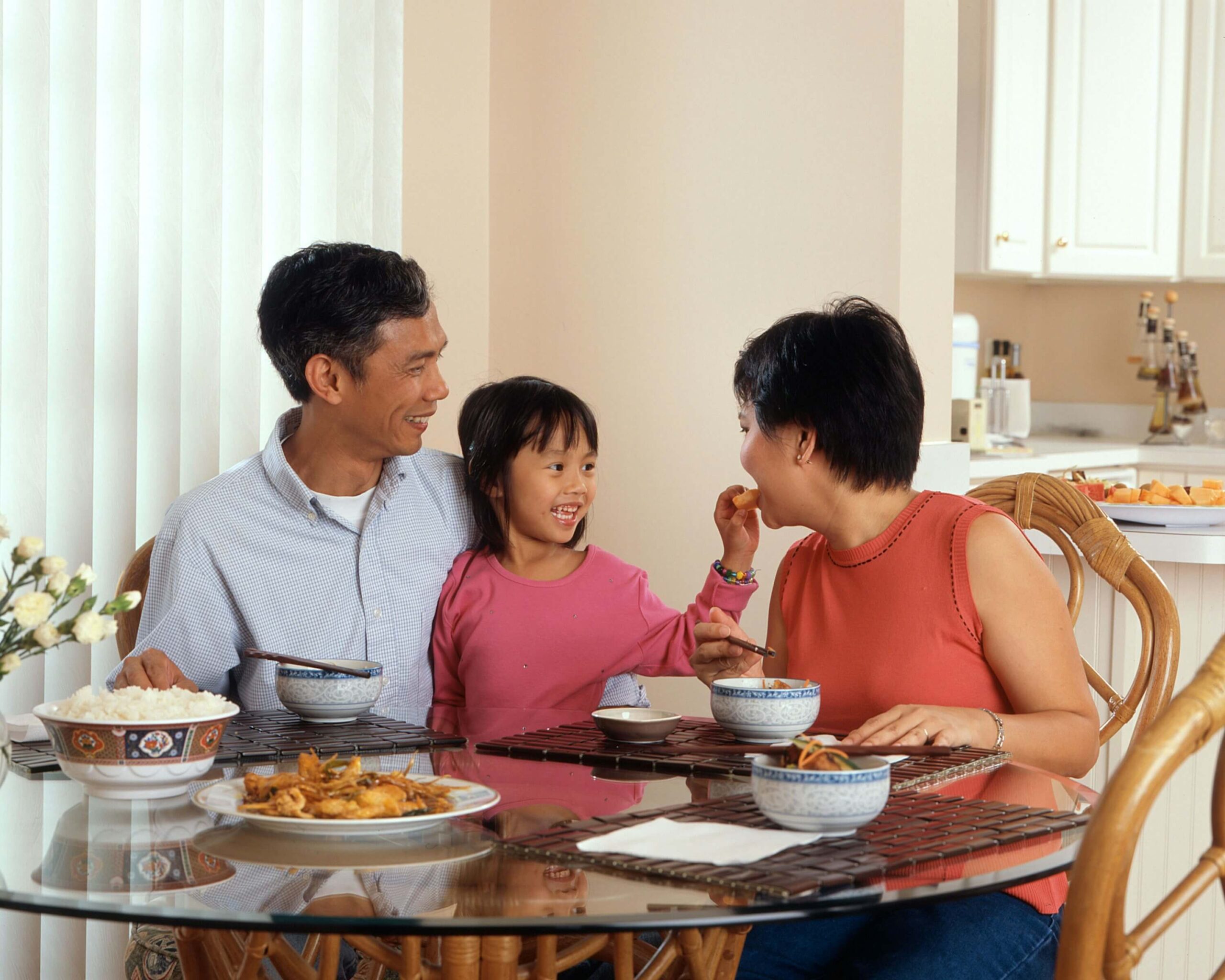 mother, father and child sitting at table enjoying a meal