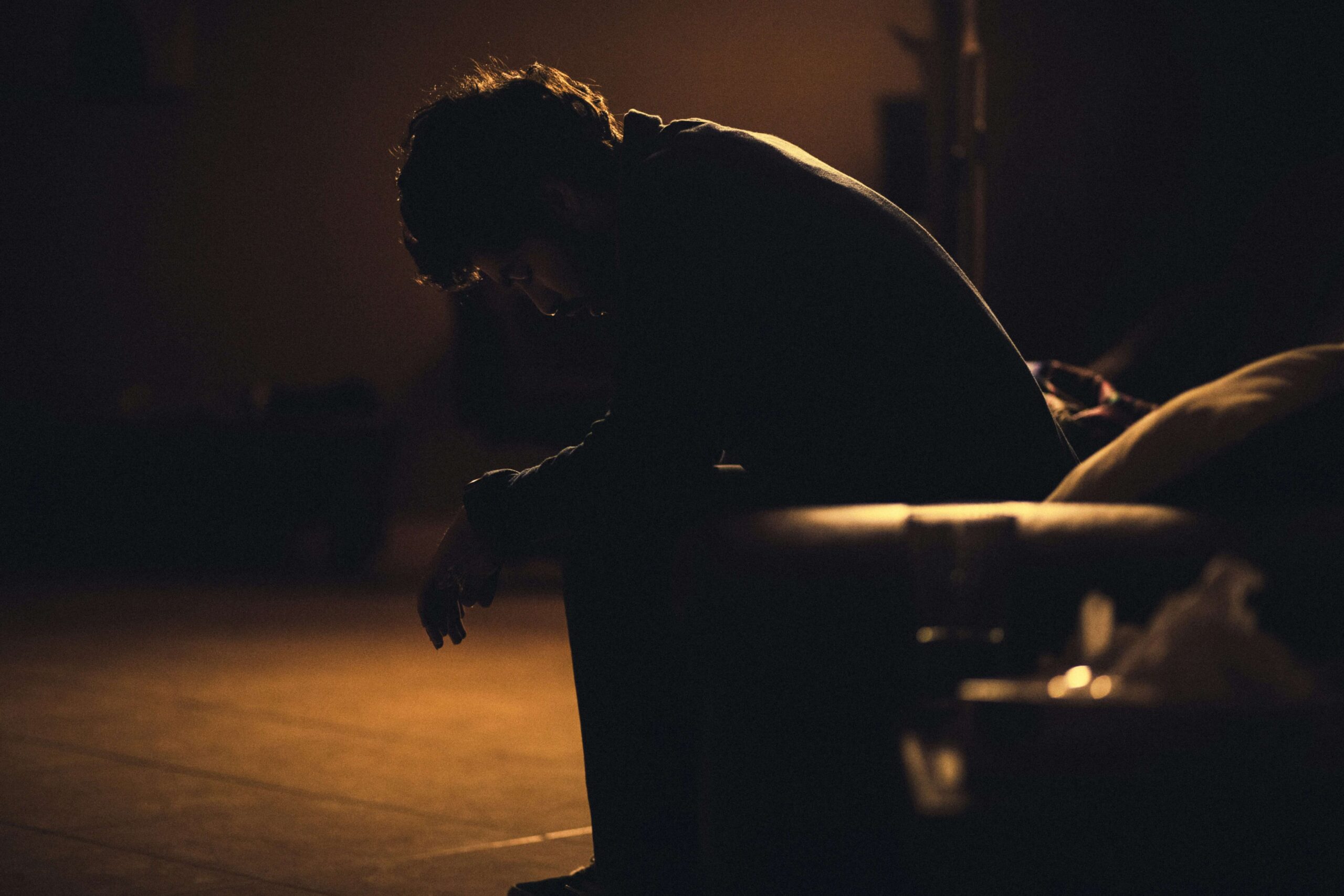 adult male sitting in chair in very dimly lit room