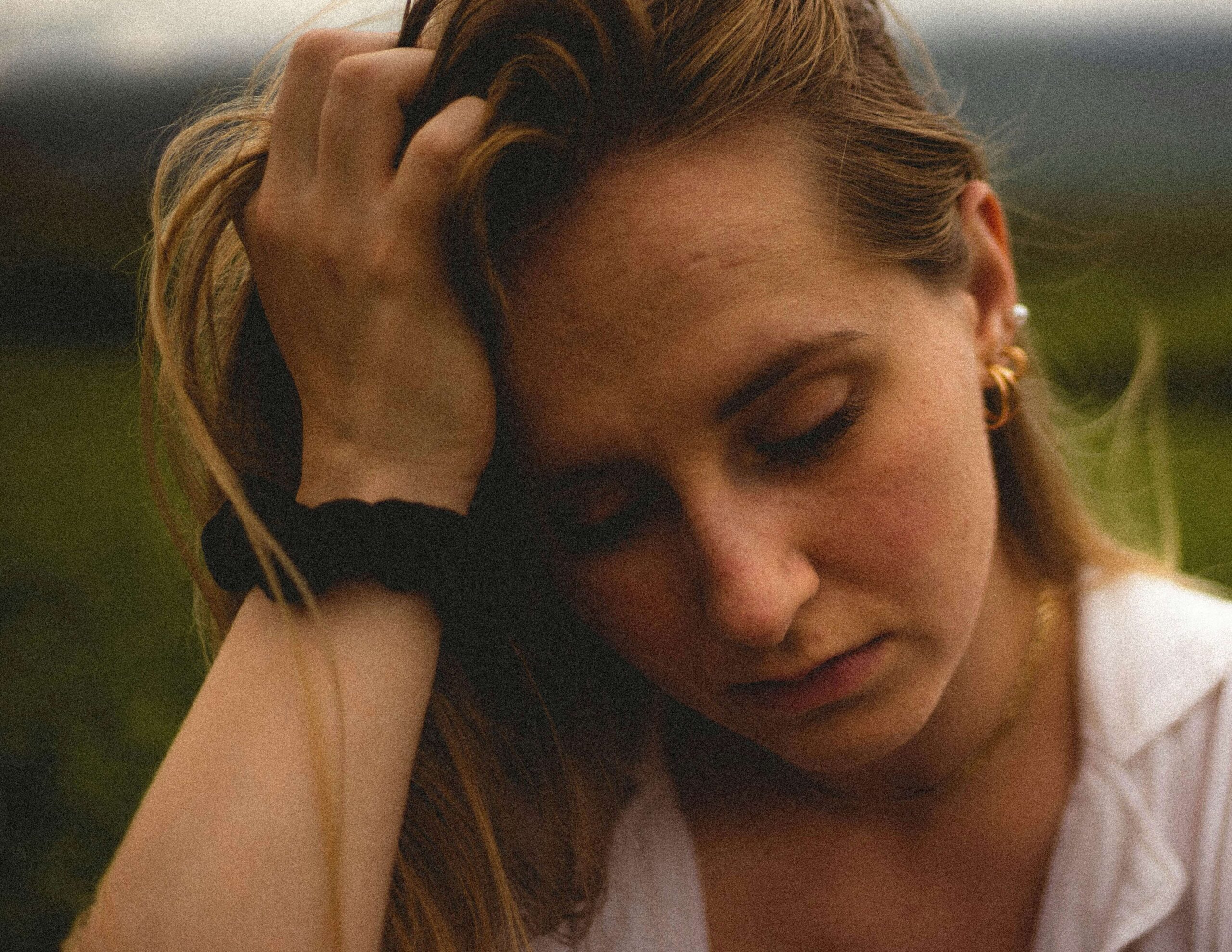 young woman sitting with hand on head