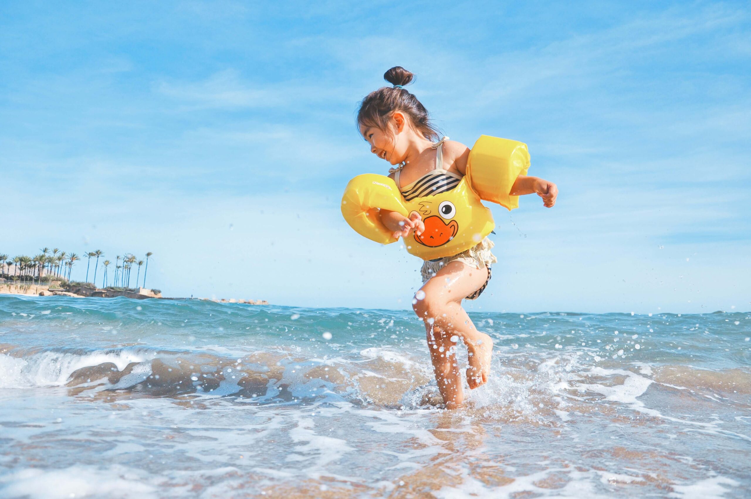 little girl wearing floaties running in ocean