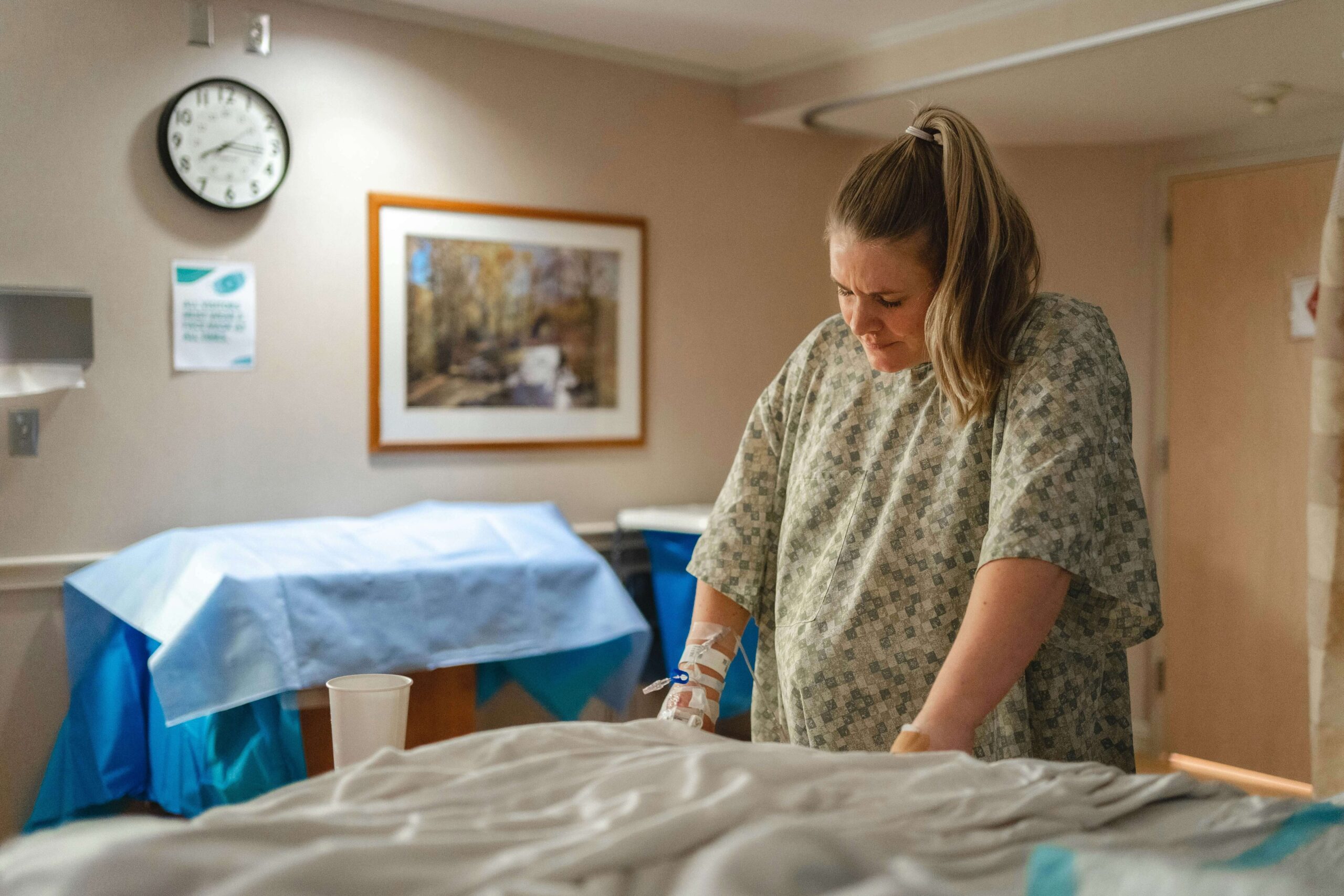 pregnant woman in hospital gown leaning up against hospital bed