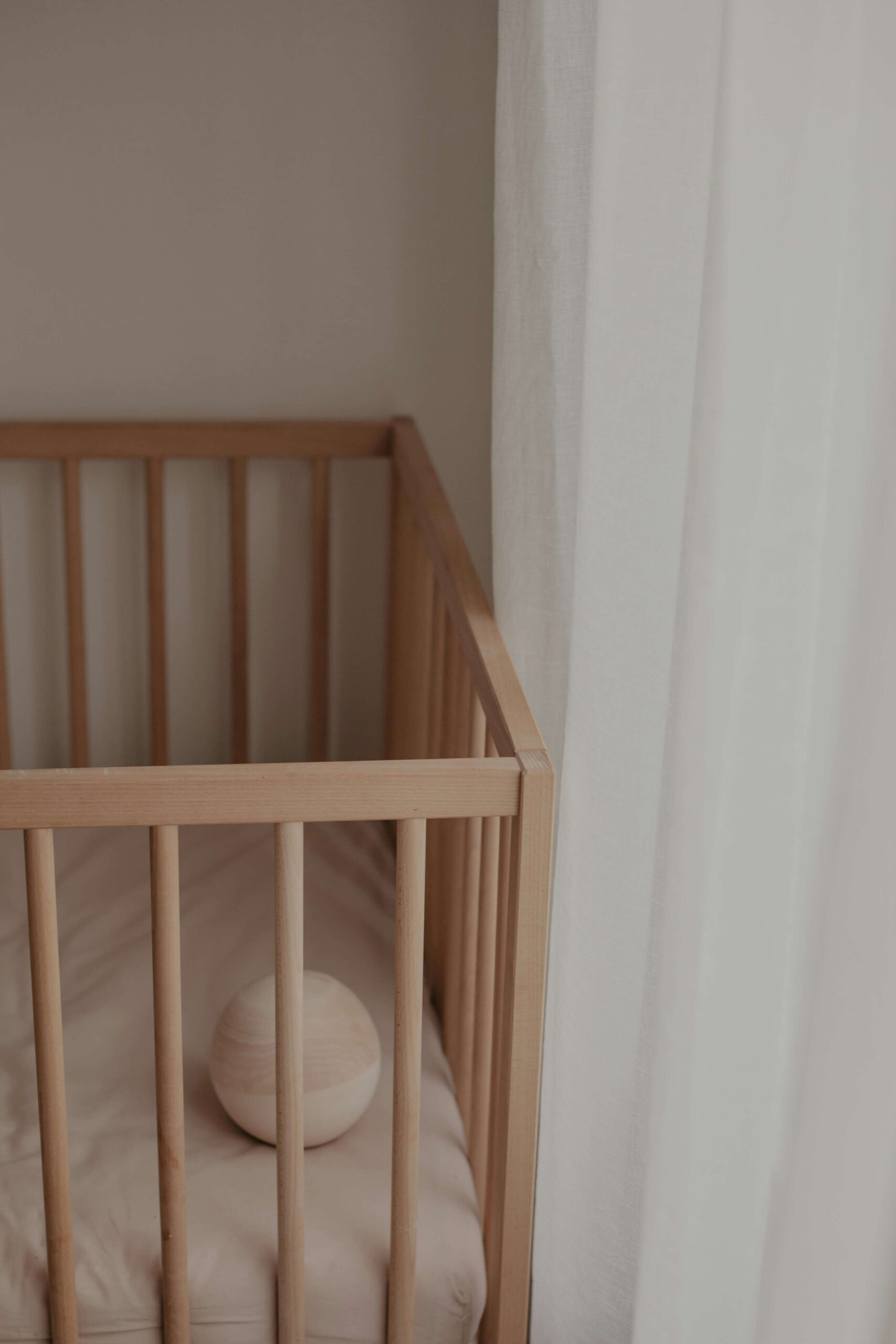 empty baby crib with ball inside next to window
