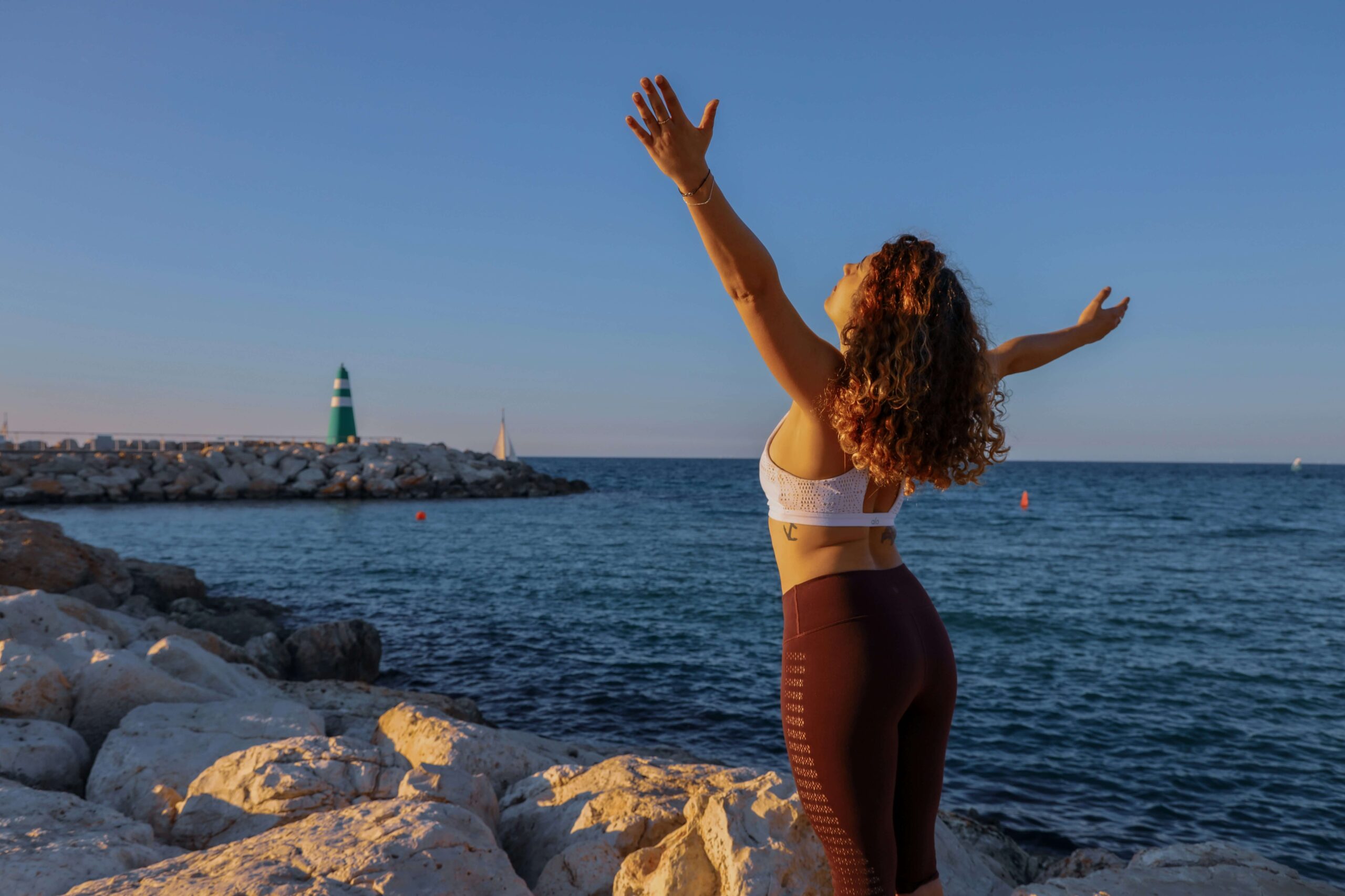 woman using mindfulness to take in world around her. open arms staring out at sky