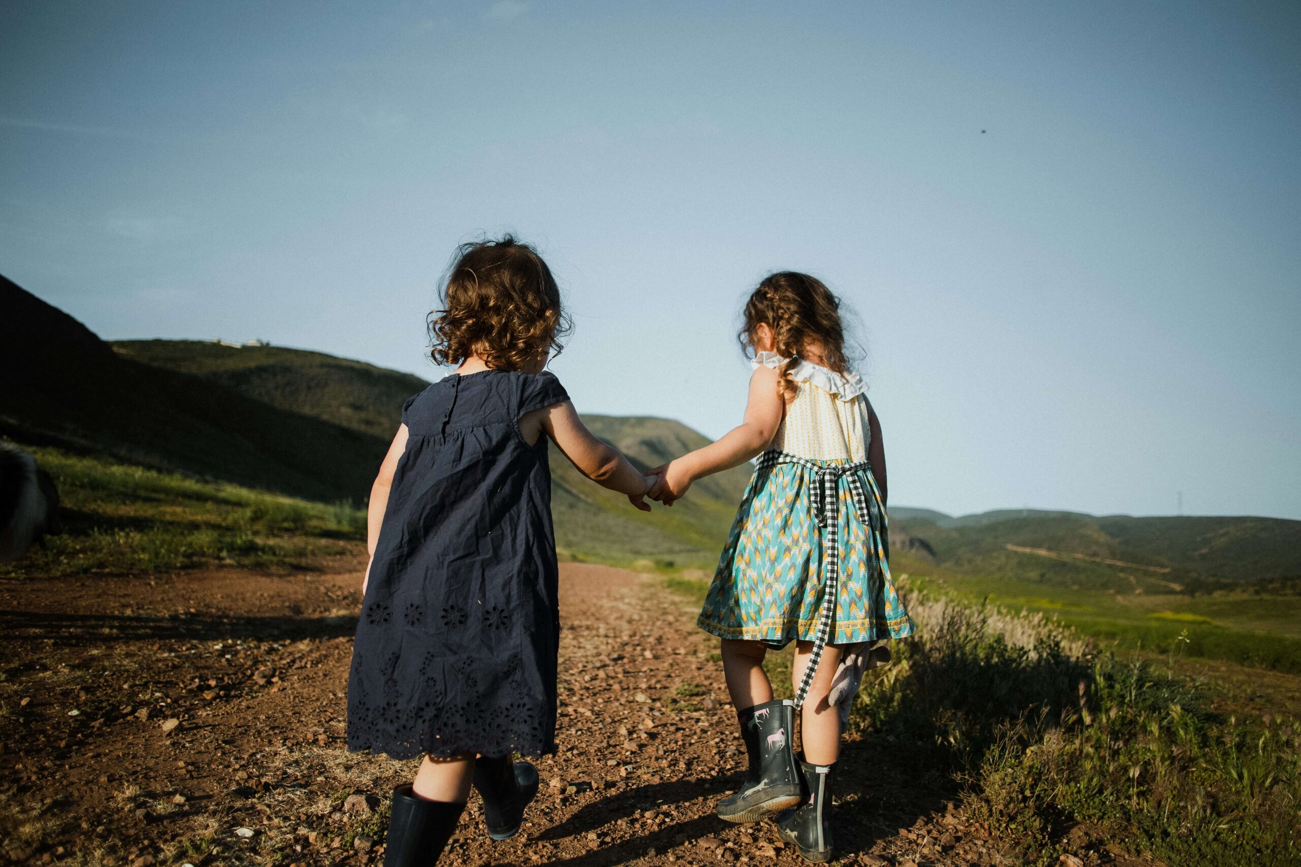 siblings holding hands walking on trail