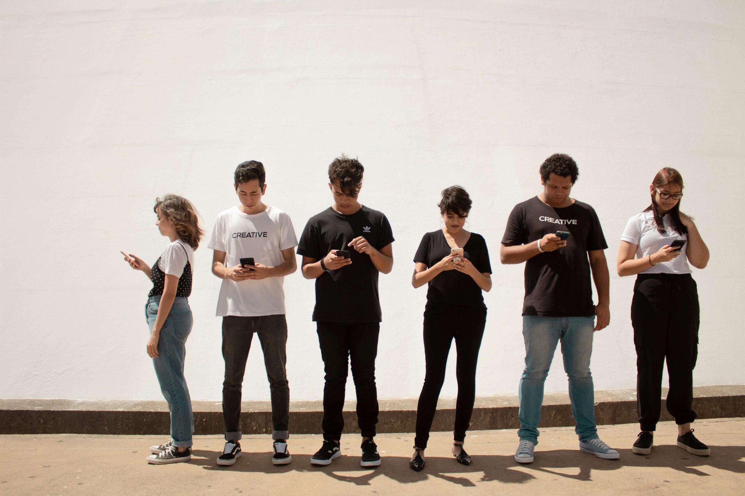 teens standing in line holding phones in hands