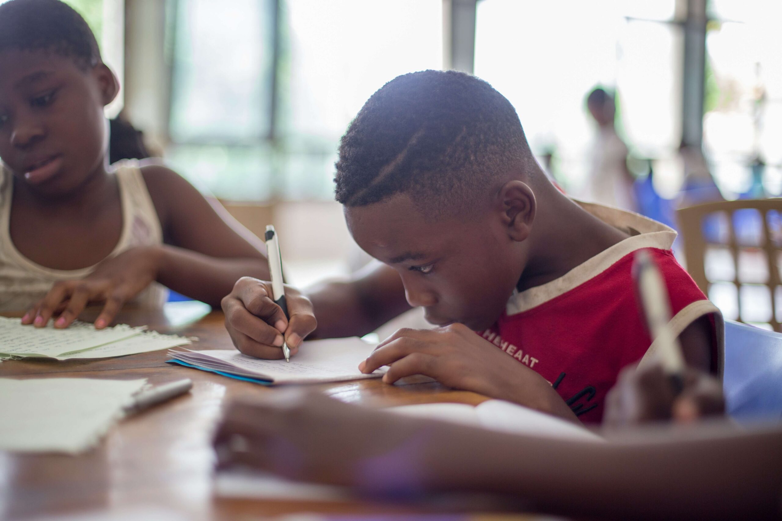 boy at desk writing on piece of paper